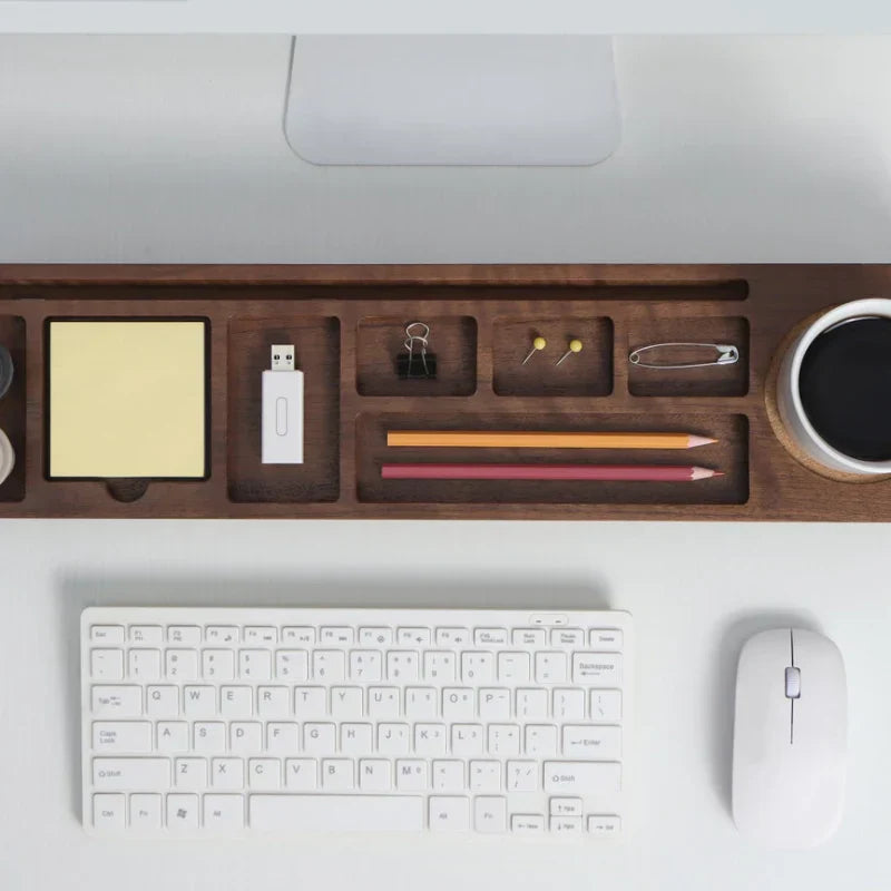 Wooden desk organizer with stationery items on a white surface with keyboard and mouse.