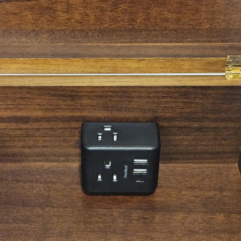 A black universal travel adapter with USB-C and USB-A ports, shown on a dark wood grain surface.