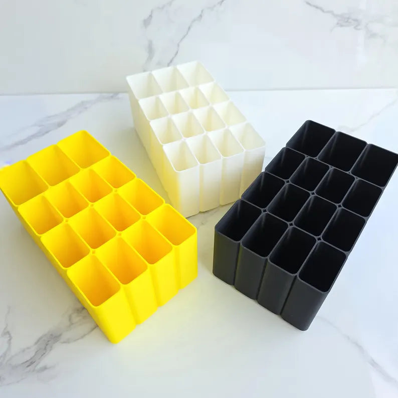 Three rectangular silicone molds in yellow, white, and black on a marble surface.